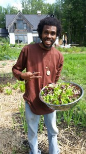 Farmer Dishaun holds a bowl of freshly harvested lettuce greens while standing in the fields by the farmhouse at Soul Fire Farm.