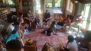 A diverse group of young farmers gather and talk in the living room of a farm house.