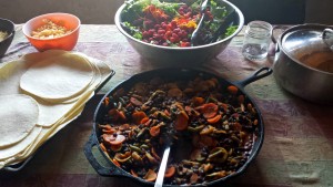 A hearty meal made from ingredients fresh off the farm: bowls of beans, tortillas, a colorful salad--spread out on a table to be shared.