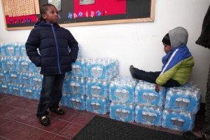 Justin Roberson (left), age 6, and Mychal Adams, age 1, wait on a stack of bottled water at a rally where the Rev. Jesse Jackson was speaking about about the water crisis in Flint, Michigan, Jan. 17, 2016. PHOTO: BILL PUGLIANO/GETTY IMAGES