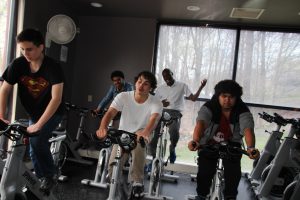 Students and a teacher exercise bikes during a spin class at the JCC.