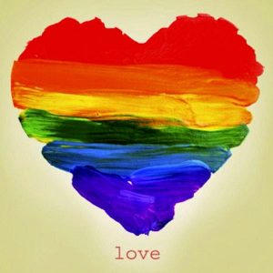 A heart painted with the pride colors and the word love beneath it.