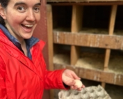Photo of Aurora holding eggs in the chicken coop.