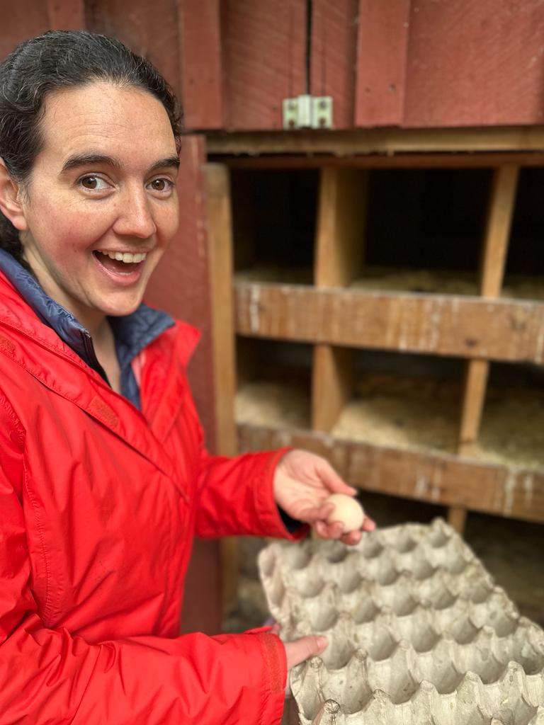 Photo of Aurora holding eggs in the chicken coop.